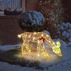 a lighted horse in the snow with lights on it's body and tail, standing next to a tree