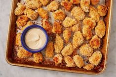 a tray filled with fried food next to a small bowl of ranch dressing on top of it