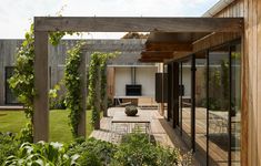 an outdoor dining area is surrounded by greenery and wooden structures, with sliding glass doors leading to the patio