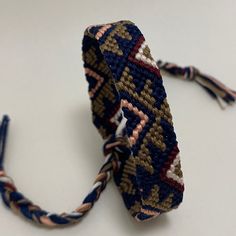 a close up of a bracelet on a white surface with blue, brown and pink colors