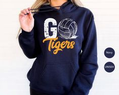 a woman wearing a hoodie that says go tigers with a volleyball ball on it