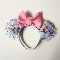 a pink bow is on top of a blue and white mouse ears with an elephant design