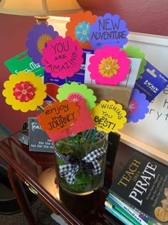 a vase filled with lots of colorful flowers on top of a table next to books