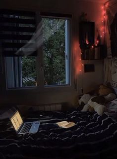 a laptop computer sitting on top of a bed in a room with lights strung from the ceiling