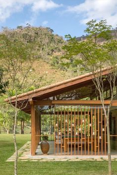 a small wooden structure sitting in the middle of a lush green field next to trees