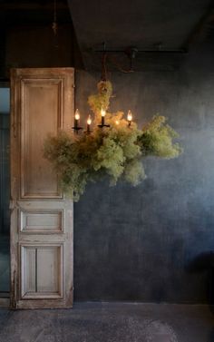 a chandelier hanging from the ceiling in front of a door with candles on it