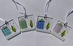 three glass ornaments hanging from strings on a white surface with green and blue decorations in them