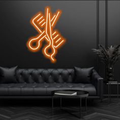 a black room with a couch, table and neon scissors on the wall above it