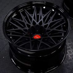 a black wheel with red logo on it sitting on top of a metal floor next to a can