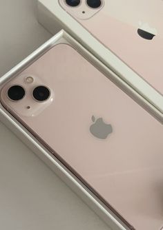 two iphones sitting next to each other on top of a white table in a box