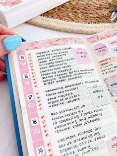 a hand holding a pen over an open planner book with numbers and words on it