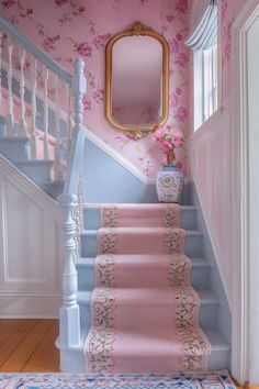 a pink and blue staircase leading up to a mirror on the wall above it is a vase with flowers