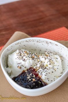 a white bowl filled with ice cream and toppings on top of a wooden table