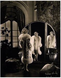 a woman standing in front of a mirror looking at herself in the mirror with fur on it