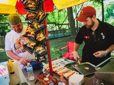 two men preparing food at an outdoor stand