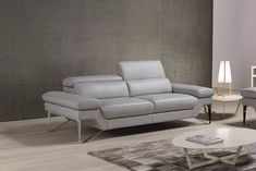 a white leather couch sitting on top of a wooden floor next to a table and lamp