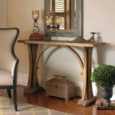 a wooden table sitting next to a white chair and a mirror on top of a wall