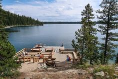 people are sitting on benches at the end of a dock overlooking a large body of water