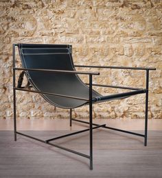 a chair sitting on top of a wooden floor next to a stone wall with a metal frame