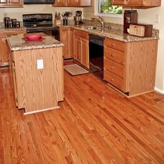 a kitchen with wooden cabinets and granite counter tops in the center, along with hardwood flooring