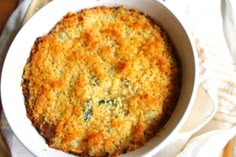 a casserole dish with cheese and spinach in it on a white cloth