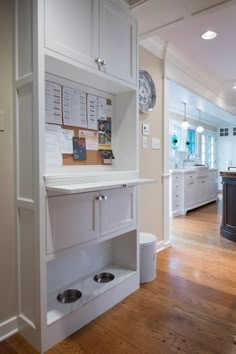 an open kitchen with white cabinets and drawers on the wall next to a wooden floor