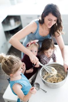 a woman and two children are mixing food in a bowl on the kitchen counter top