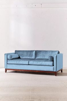 a blue couch sitting on top of a hard wood floor next to a white wall