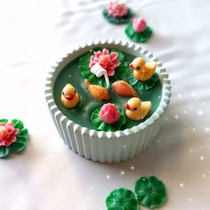 a bowl filled with green water and little rubber ducks floating on top of the water