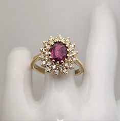 a close up of a ring with a pink stone in the middle and white stones around it