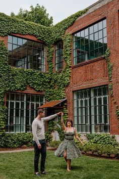 a man standing next to a woman in front of a building covered in vines and ivy