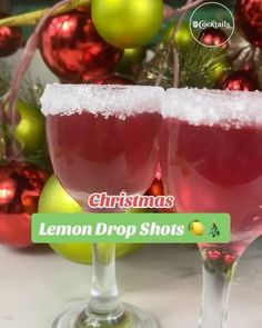 two glasses filled with lemon drop shots sitting on top of a table next to christmas ornaments