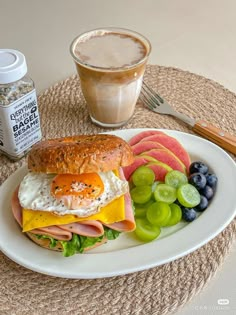 a breakfast sandwich on a plate with fruit and coffee