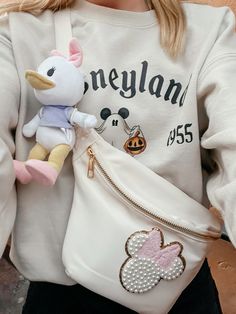 The viral sweatshirt of this season is just as good as you could imagine, plus adding my favorite belt bag and nuimo combo 💜🩷 Purse For Disney World, Diy Disney Belt Bag, Disney Nuimos Outfit, Disneyland Crewneck, Fanny Pack Outfits, Disney Belt Bag, Disney Nuimos On Bag, Disney Crossbody Bags For Disney Trips, Disney Winter Outfits