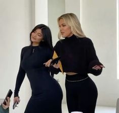 two women in black outfits standing next to each other