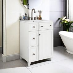 a white sink sitting under a mirror next to a bath tub in a room with gray walls