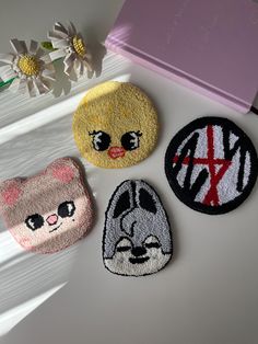 three patches with cartoon characters on them sitting next to flowers and a pink box in the background