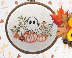 a cross stitch pattern with a ghost and pumpkins in the fall leaves on a white background