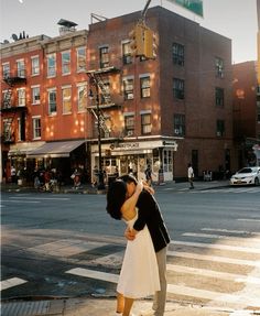 a man and woman are kissing on the crosswalk in front of an apartment building