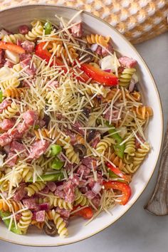 a bowl filled with pasta and meat on top of a white table next to utensils