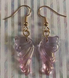 a pair of pink glass earrings with gold earwires on a striped table cloth