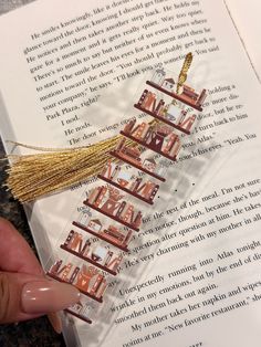 a hand is holding a bookmark that has pictures on it with tassels