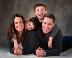 a family posing for a photo with their two children in front of a gray background