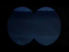 an image of the moon seen through two circles in the dark night sky, with only one light visible