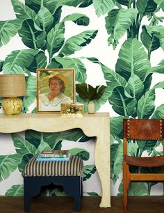 a living room with a table, chair and wallpaper that has green leaves on it