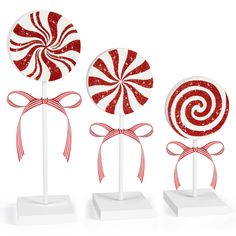 three red and white lollipops with bows on them are standing in front of each other