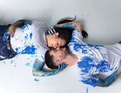 two people laying on the ground covered in blue paint