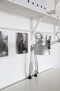 a desk lamp sitting on top of a table next to pictures hanging on the wall