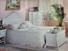 a white bed sitting in a bedroom next to a dresser and window covered with curtains