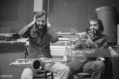 two men sitting next to each other in front of a recording studio with musical instruments